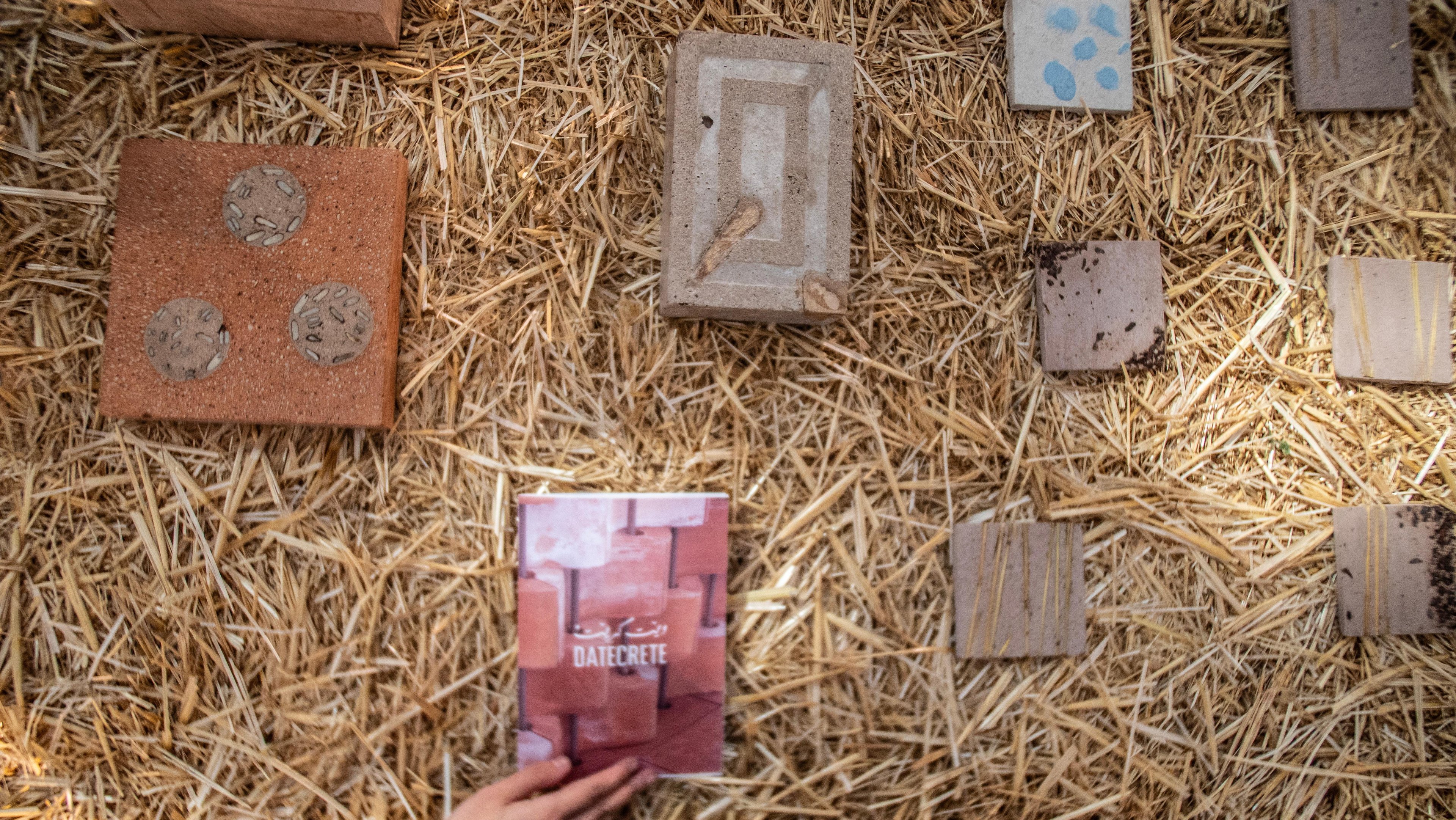 Close up shot of Datecrete tiles and customized formats on a wheat-stalk platform, along with a Datecrete catalog.