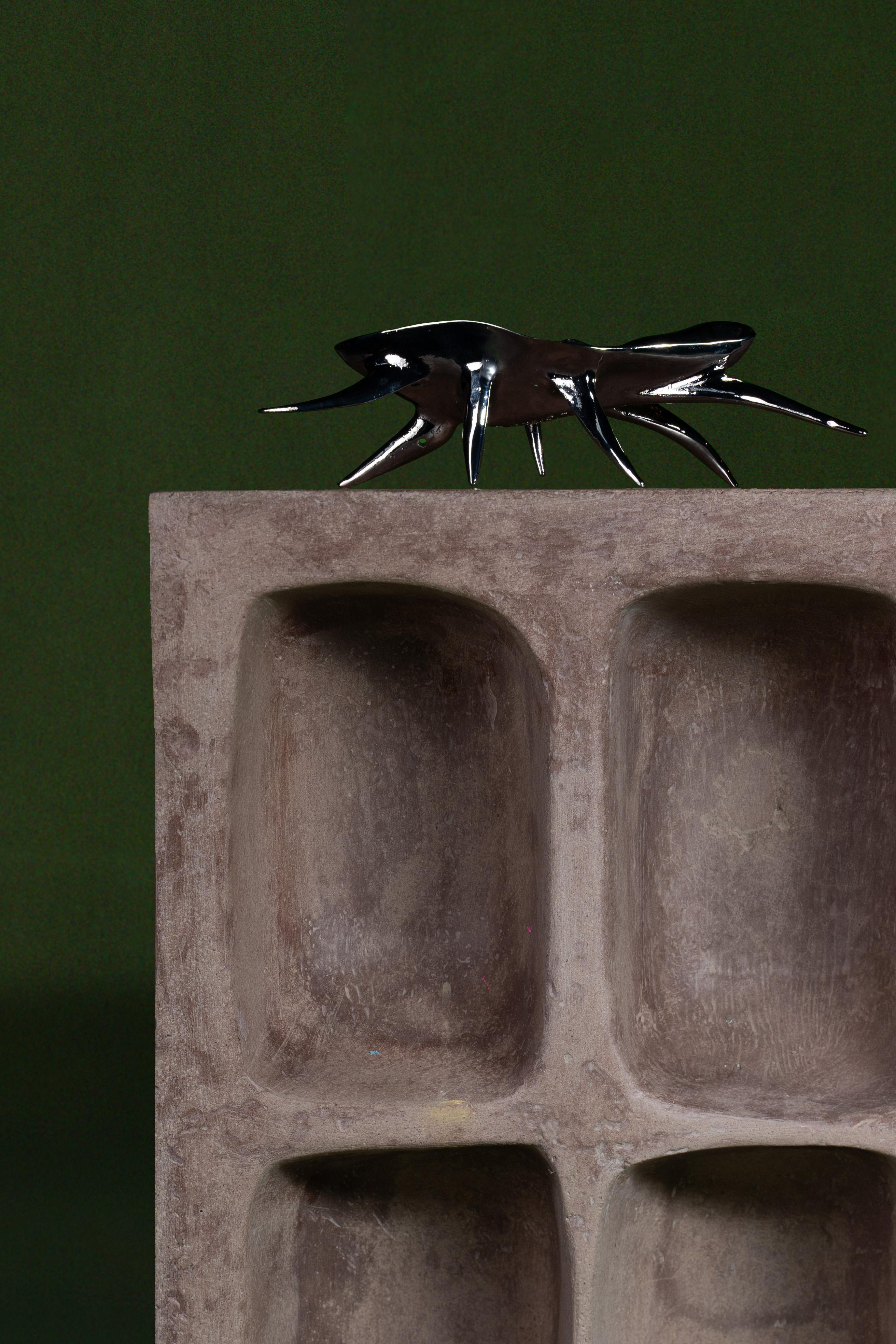 Close-up shot of the top of the Datecrete Vessel, photographed with a decorative metallic insect statue.